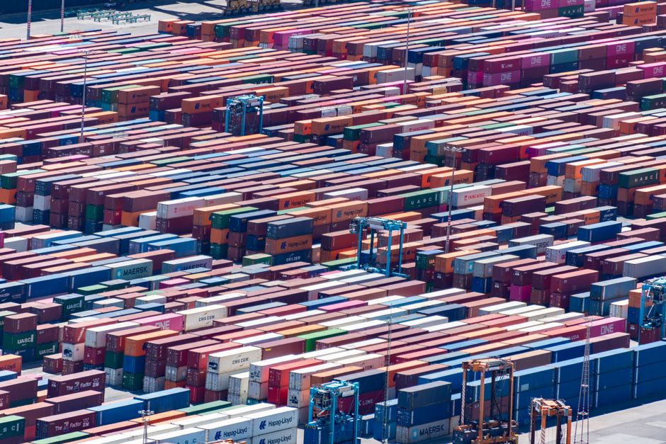 Colorful shipping containers stacked at a busy port, aerial view.